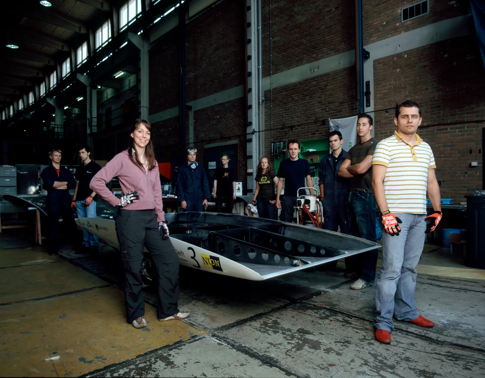 The Nuna4 team in their workshop, surrounding their car. Tine is the person on the left, wearing a pink sweater and gloves