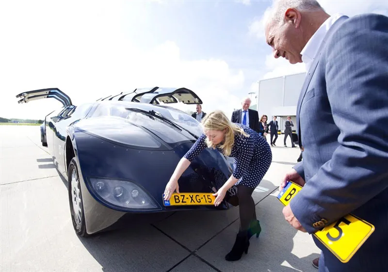 Wubbo Ockels (on the right) looks at Superbus, a concept car for an electric bus with gull-wing doors, as it receives its licence plate